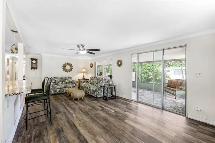 Living room with ornamental molding, dark hardwood / wood-style flooring, and ceiling fan