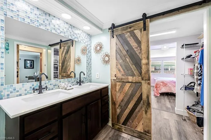 Bathroom featuring vanity, ornamental molding, decorative backsplash, and hardwood / wood-style flooring
