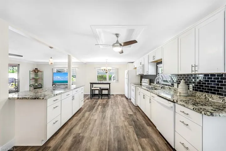 Kitchen featuring hanging light fixtures, white appliances, white cabinetry, dark hardwood / wood-style floors, and ceiling fan