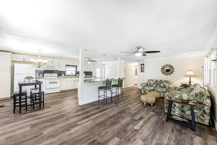 Living room featuring ceiling fan with notable chandelier, dark hardwood / wood-style flooring, and sink