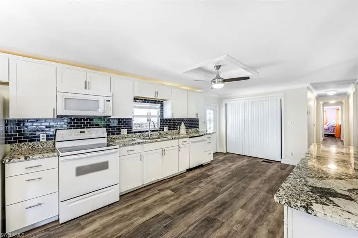 Kitchen featuring ceiling fan, sink, white appliances, and white cabinets