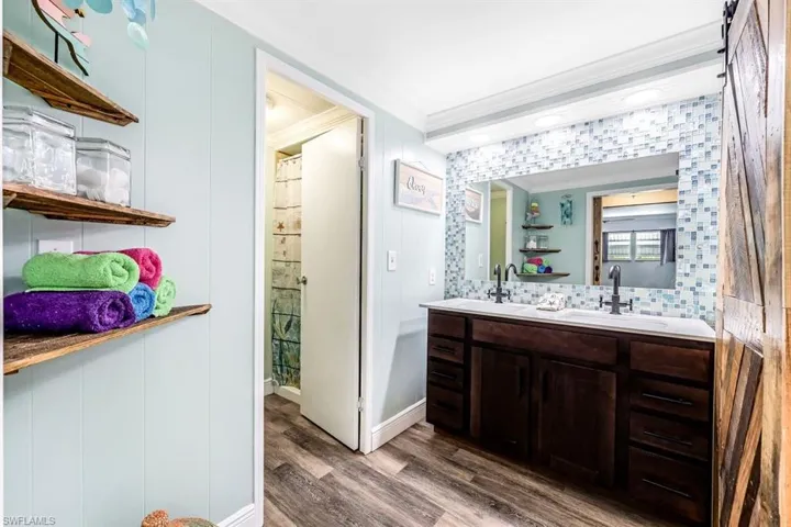 Bathroom featuring ornamental molding, vanity, wood-type flooring, and decorative backsplash