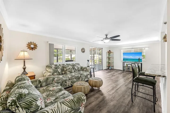 Living room featuring ornamental molding, dark hardwood / wood-style flooring, and ceiling fan