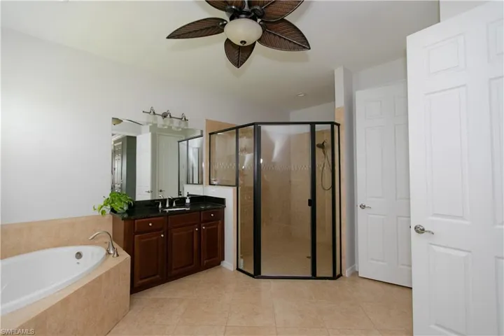 Full bathroom featuring vanity, tile floors, a shower stall, ceiling fan, and a garden tub