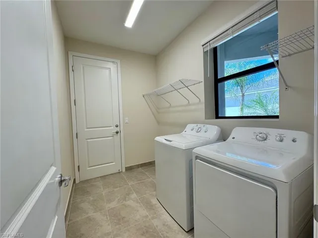Laundry area with washing machine and dryer and light tile patterned floors