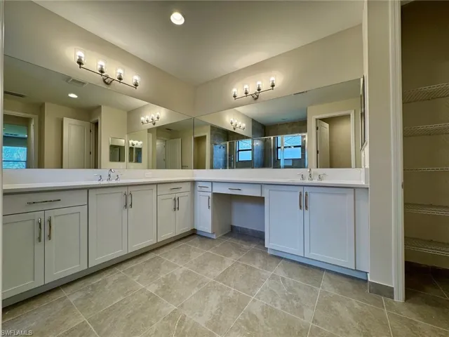 Bathroom featuring a shower stall, vanity, a spacious closet, light tile patterned flooring, and recessed lighting