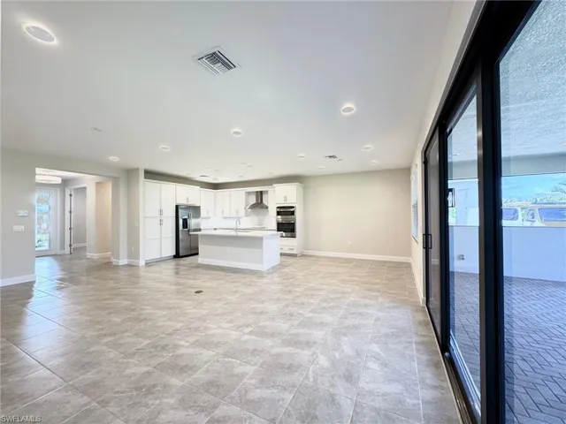 Kitchen featuring white cabinets, stainless steel appliances, light countertops, a kitchen island with sink, and open floor plan