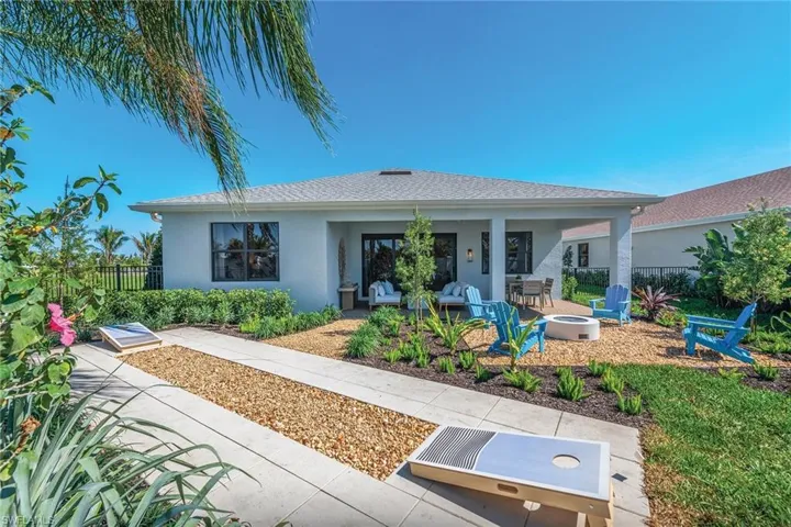 Rear view of house with an outdoor fire pit, a patio area, stucco siding, and roof with shingles