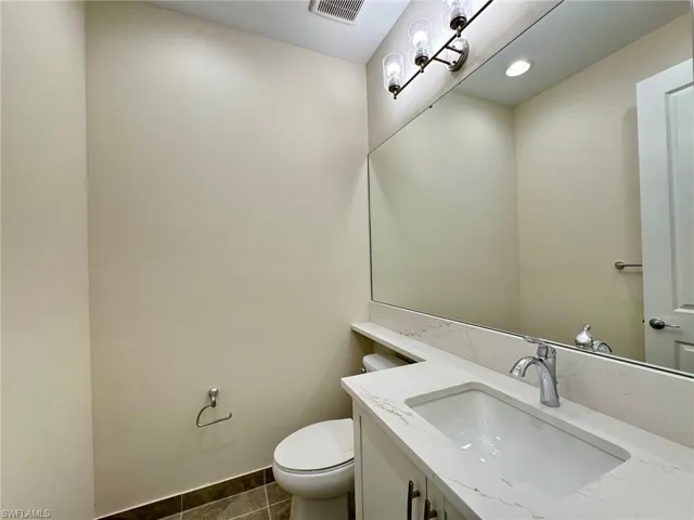 Half bath featuring vanity and dark tile patterned floors