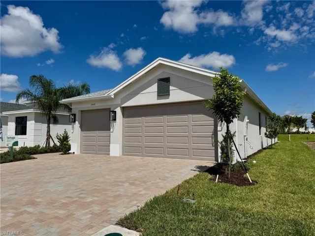 View of front of property with stucco siding, decorative driveway, an attached garage, and a front yard