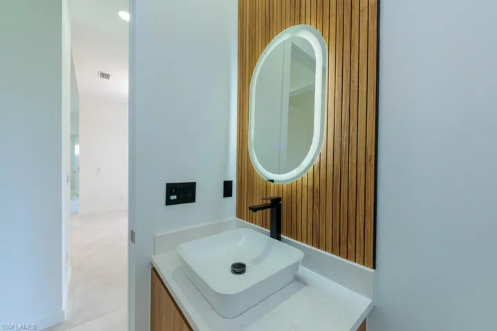 Bathroom with vanity, tile patterned flooring, and wood walls