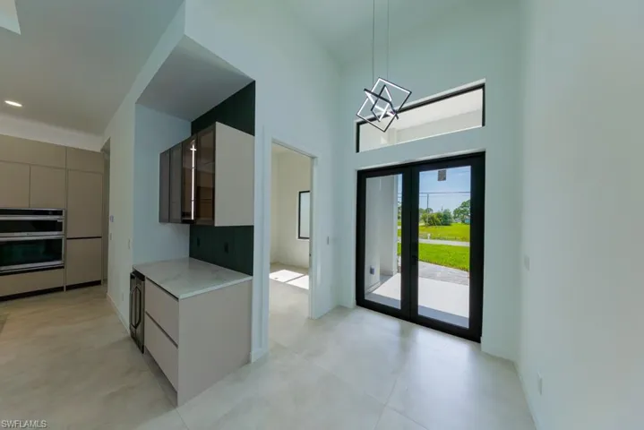 Kitchen with stainless steel double oven, modern cabinets, gray cabinetry, a chandelier, and pendant lighting