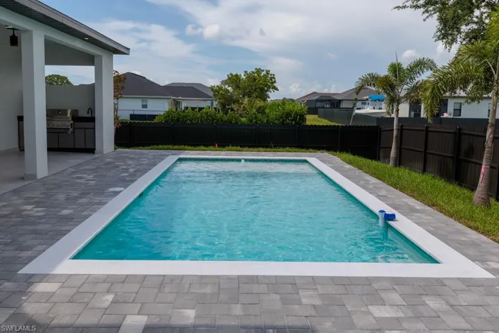 View of pool with an outdoor kitchen, a fenced backyard, a patio area, and a residential view