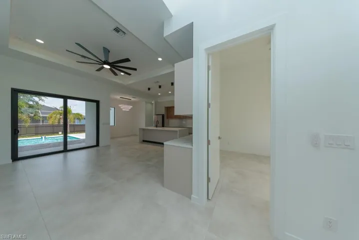 Kitchen featuring a tray ceiling, ceiling fan, light countertops, freestanding refrigerator, and white cabinetry