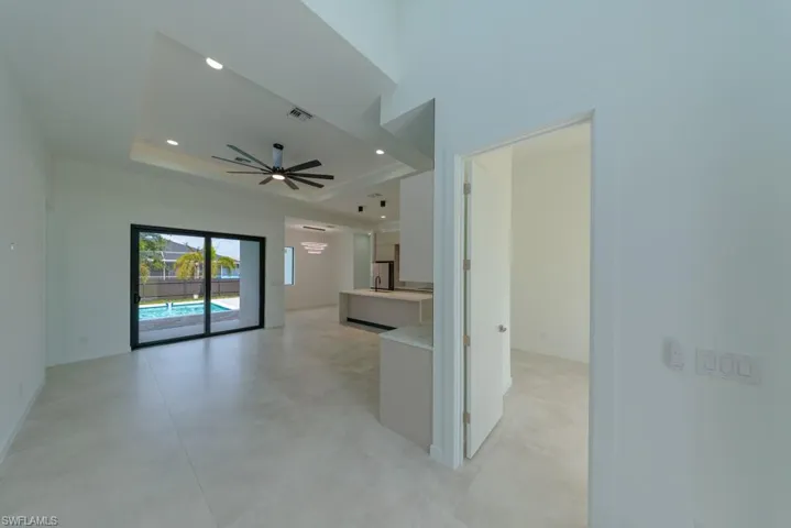 Unfurnished living room with ceiling fan, a raised ceiling, recessed lighting, and light tile patterned flooring