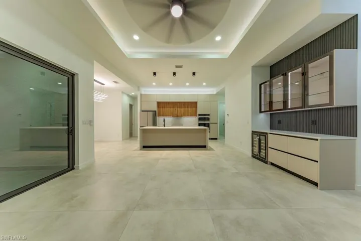 Kitchen with freestanding refrigerator, light countertops, an island with sink, recessed lighting, and modern cabinets
