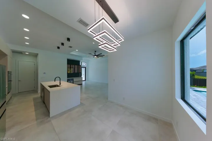 Kitchen with a ceiling fan, recessed lighting, an island with sink, pendant lighting, and a chandelier