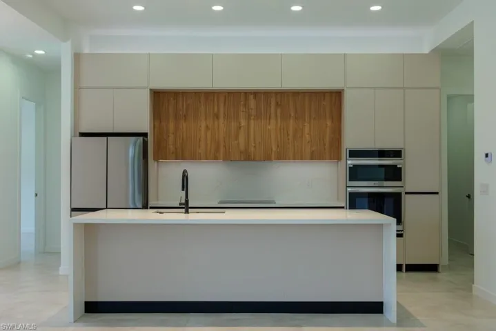 Kitchen with freestanding refrigerator, double oven, modern cabinets, recessed lighting, and backsplash