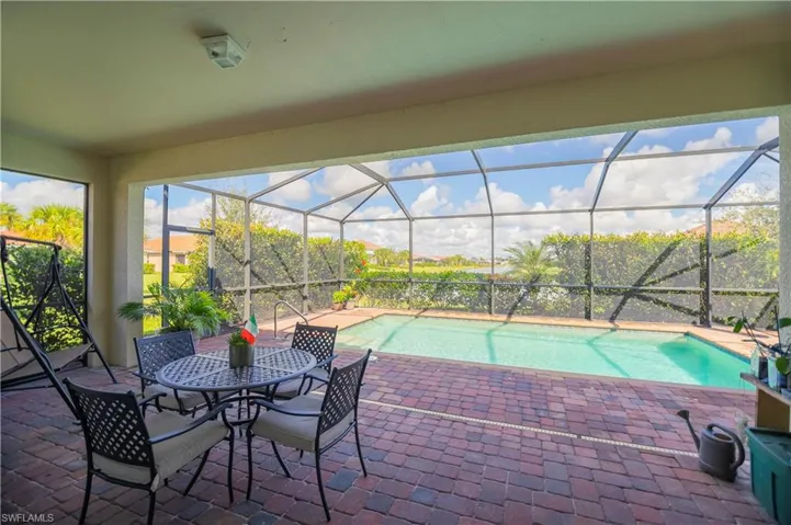Swimming pool with a sunroom, glass enclosure, a patio, and outdoor dining space