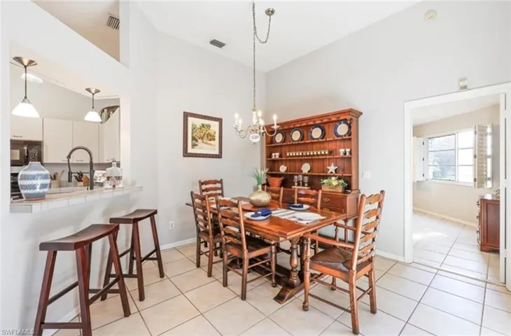 Dining space with visible vents, high vaulted ceiling, a notable chandelier, and light tile patterned flooring