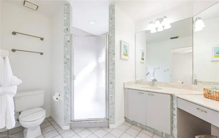 Full bath featuring a shower stall, tile patterned flooring, visible vents, toilet, and vanity