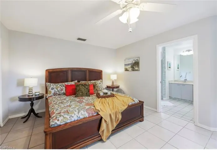 Bedroom featuring connected bathroom, baseboards, visible vents, and light tile patterned floors