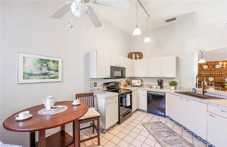Kitchen with light countertops, high vaulted ceiling, a sink, and black appliances