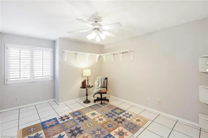 Living area with a ceiling fan, baseboards, and light tile patterned floors