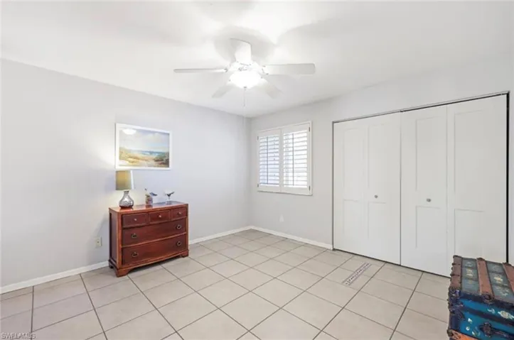 Unfurnished bedroom featuring light tile patterned floors, baseboards, a ceiling fan, and a closet