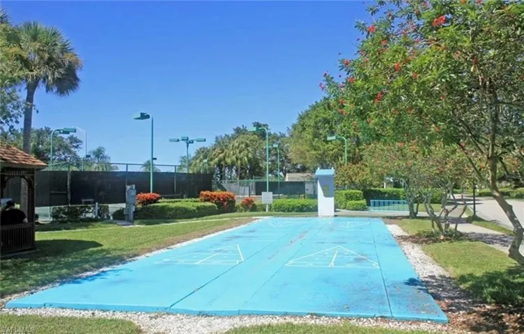 View of community with a lawn, fence, and shuffleboard