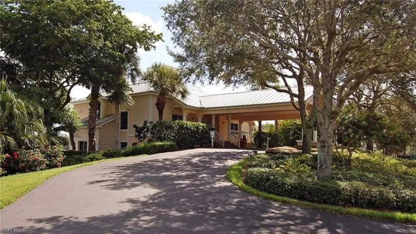 View of front facade featuring a carport, curved driveway, and metal roof