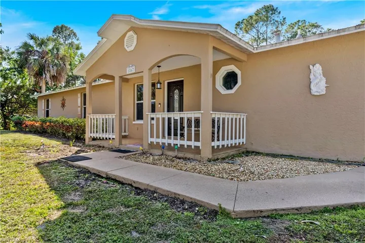 Property entrance featuring covered porch, stucco siding, and a yard