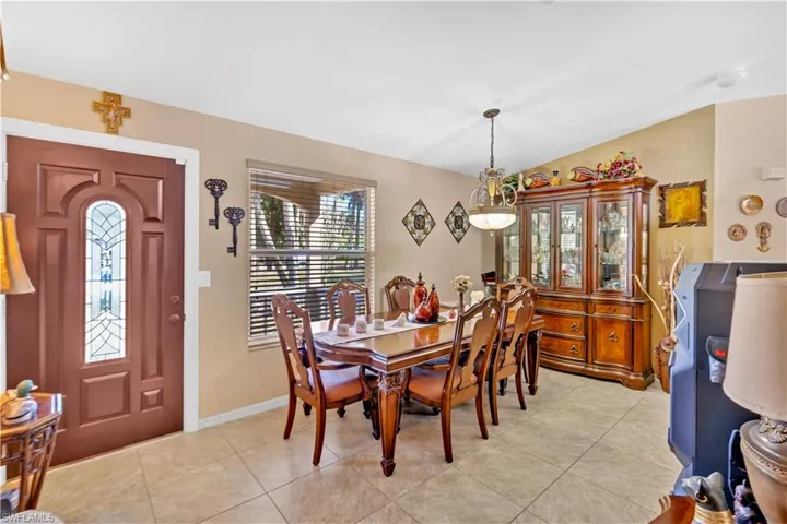 Dining area with light tile patterned floors and vaulted ceiling