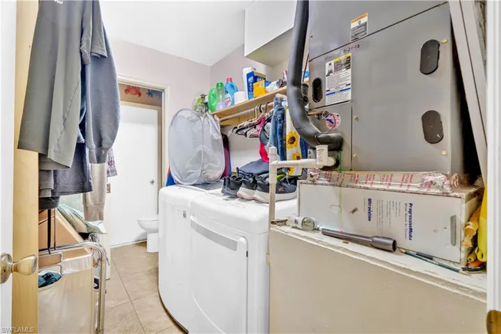Laundry area featuring heating unit, light tile patterned flooring, and washer and clothes dryer