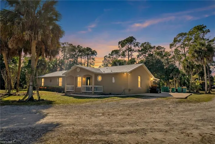 View of front of property featuring a standing seam roof, stucco siding, covered porch, and a front lawn