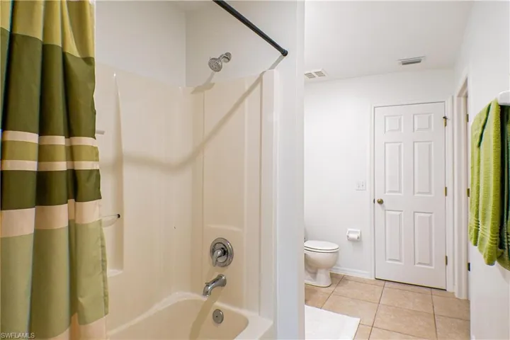 Bathroom with toilet, tile patterned flooring, and shower / bath combo with shower curtain