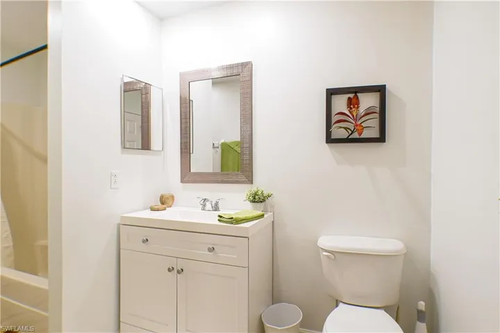 Bathroom with toilet, vanity, and a shower with shower curtain