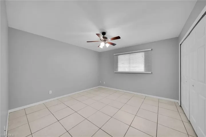 Spacious room featuring neutral grey walls and light-toned square tile flooring