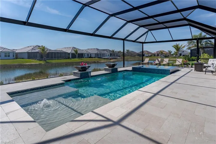 View of pool featuring a patio area, a residential view, a water view, a pool with connected hot tub, and glass enclosure
