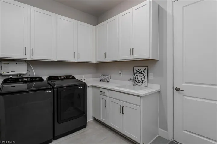Laundry room with washing machine and clothes dryer, cabinet space, and light tile patterned floors