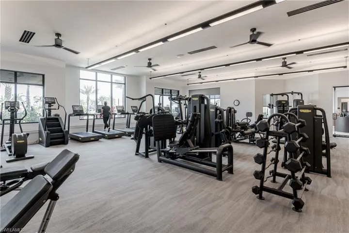 Exercise room with ceiling fan and light carpet