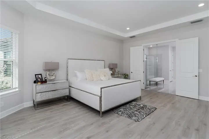 Bedroom with multiple windows, recessed lighting, wood finished floors, and a raised ceiling