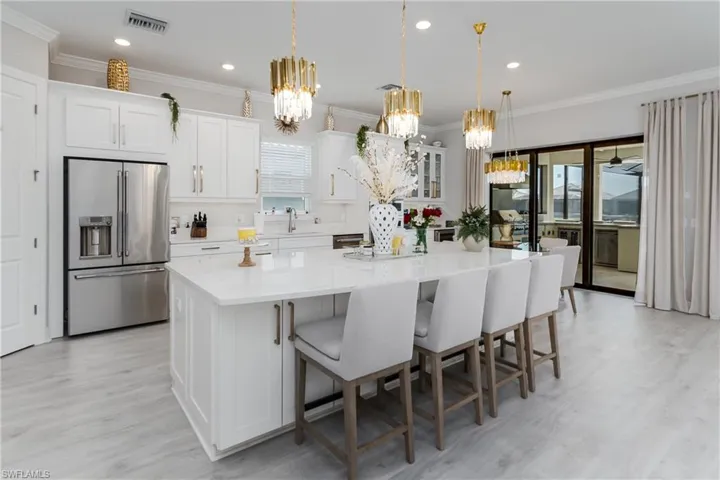 Kitchen featuring built in fridge, a chandelier, a center island, healthy amount of natural light, and ornamental molding