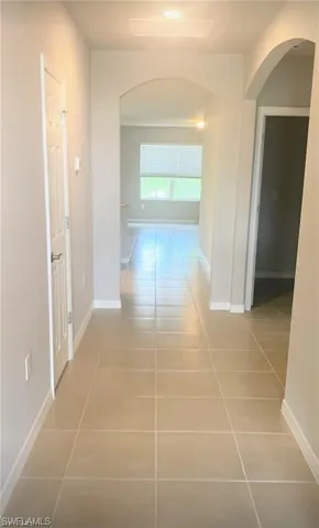Hallway featuring arched walkways and light tile patterned floors
