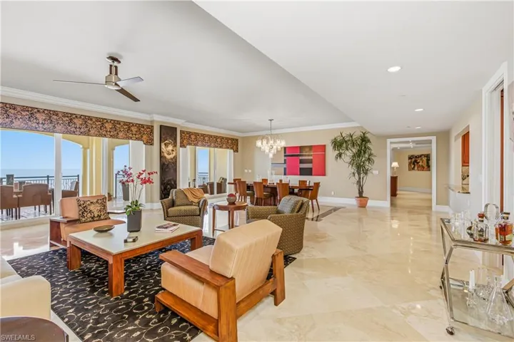 Living area with a chandelier, crown molding, a ceiling fan, light marble finish floors, and recessed lighting