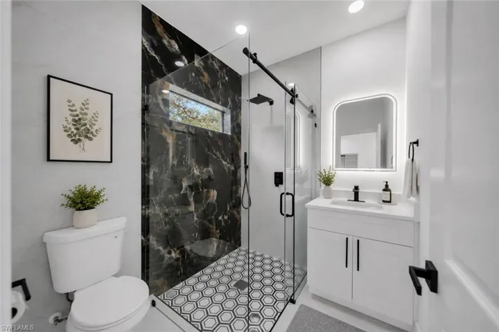 Modern bathroom featuring a walk-in shower with black-veined wall tile, hexagonal floor tile, and a glass enclosure