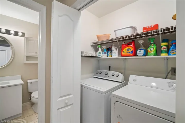 Clothes washing area featuring light tile patterned floors and washing machine and clothes dryer