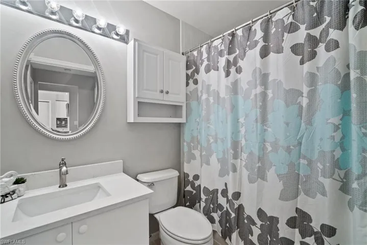Bathroom featuring a shower with shower curtain, vanity, and toilet