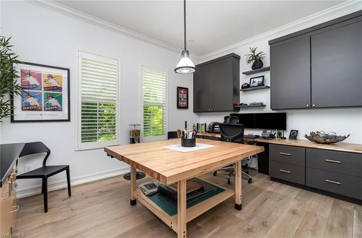 Dining area with light wood-type flooring, ornamental molding, and built in desk