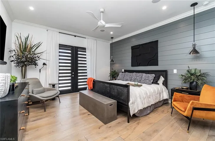 Bedroom featuring ceiling fan, wood walls, crown molding, and light hardwood / wood-style floors